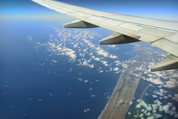View through airplane window of commercial jet plane wing flying high in the sky. Air travelling concept