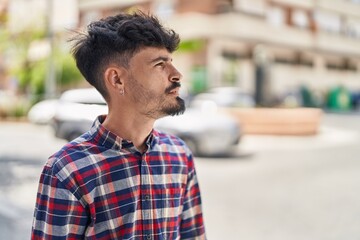 Young hispanic man looking to the side with relaxed expression at street