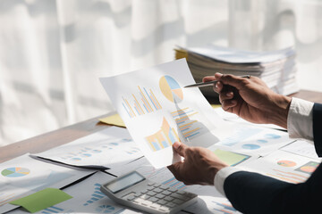 Business man checking financial documents, he owns a startup company, he sits checking the company's financial summary prepared by the finance department. Management concept of startup company.