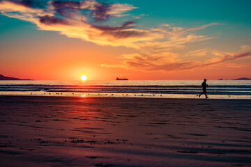 silhouette of person exercising running on the seashore at sunset