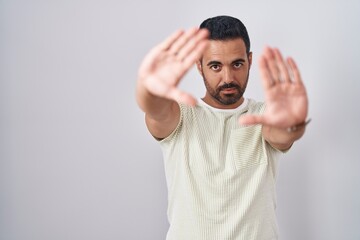 Hispanic man with beard standing over isolated background doing frame using hands palms and fingers, camera perspective