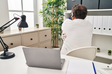 Senior doctor man working on online appointment hugging oneself happy and positive from backwards. self love and self care