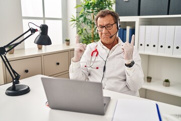 Senior doctor man working on online appointment pointing up looking sad and upset, indicating direction with fingers, unhappy and depressed.