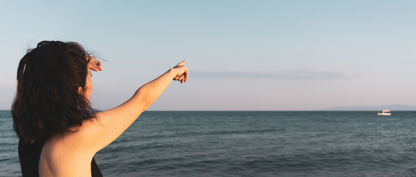 Woman pointing distant empty blue sky. High resolution photo image can be used as large printed canvas, website banner, social media post. Blank copy space for advertising texts.