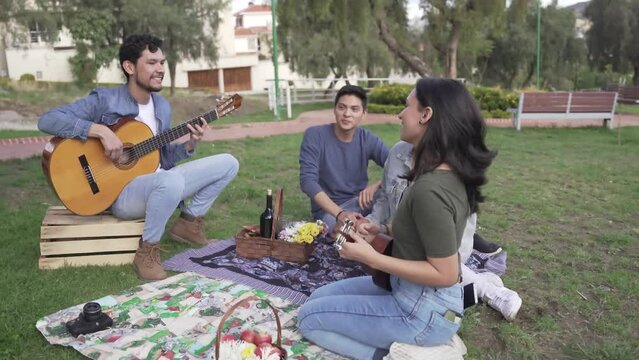 Multi-ethnic group of young people singing playing guitar and ukulele outdoors