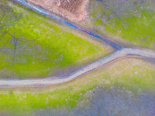 An aerial shot of the landscape with small lake surrounded by trees and field