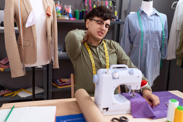 Non binary man tailor stressed using sewing machine at atelier