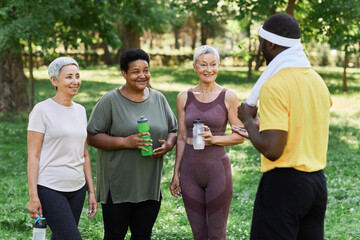 Diverse group of senior women enjoying outdoor sports training and talking to coach