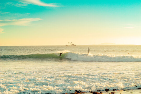 surfer on baja california beach with boat in the background