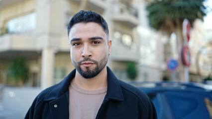 Young arab man standing with serious expression at street