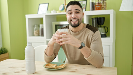 Young arab man having breakfast sitting on table at home