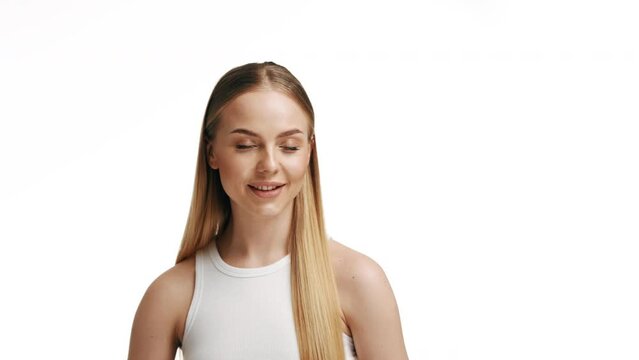 A luxurious blonde combs her long hair. Blonde girl smiling on a white background with a comb.