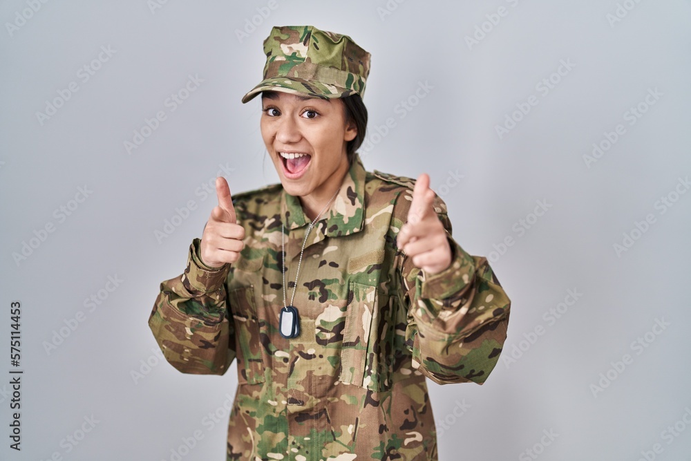 Poster young south asian woman wearing camouflage army uniform pointing fingers to camera with happy and fu