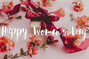 Happy womens day text and stylish gift box with flowers on pink background. Greeting card....