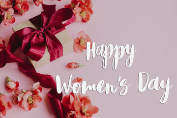 Fototapeta na wymiar Happy womens day text and stylish gift box with flowers on pink background. Greeting card. Handwritten sign and present for international women's day. 8 march