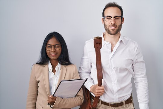 Interracial business couple wearing glasses winking looking at the camera with sexy expression, cheerful and happy face.