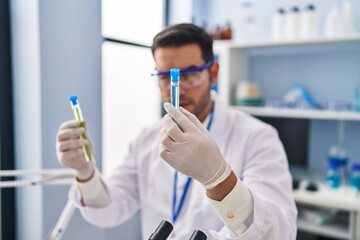 Young hispanic man scientist holding test tubes at laboratory