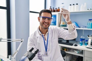 Young hispanic man scientist holding test tube at laboratory