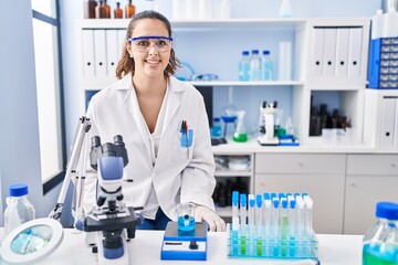 Fototapeta premium Young hispanic woman working at scientist laboratory with a happy and cool smile on face. lucky person.