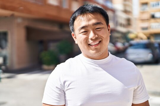 Young chinese man smiling confident standing at street