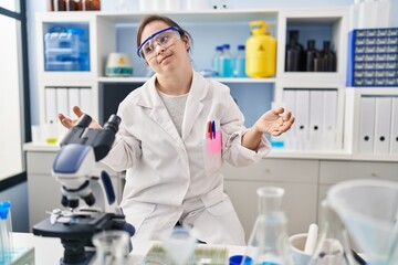 Hispanic girl with down syndrome working at scientist laboratory clueless and confused with open arms, no idea concept.