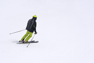 Ski season. A lone figure of a skier on a white, snow-covered slope. Copy space.