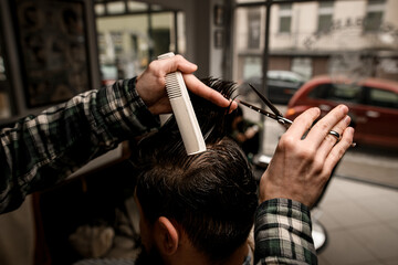 great close-up view of hands of barber master making haircut to client