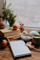 a notebook with blank pages next to books and tangerines, handmade candles. Plans and dreams for the new year