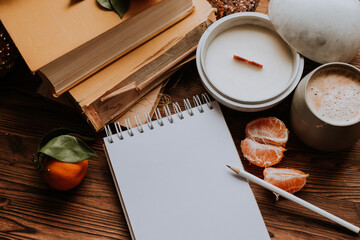 a notebook with blank pages next to books and tangerines, handmade candles. Plans and dreams for the new year