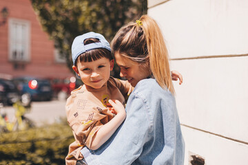 Happy mom holding son boy in arms, hugging kid with noses touch, smiling, enjoying warm moment....