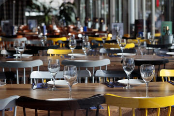 Casual restaurant interior with empty glasses and tables with yellow chairs