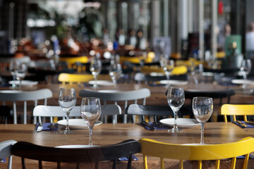 Casual restaurant interior with empty glasses and tables with yellow chairs