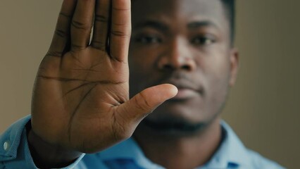 Strong African American 30s man businessman office agent male guy stand indoors outstretch palm stop hold hand in front protect no defense rejection keep distance protest against ethnic discrimination