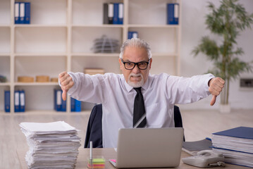 Obraz premium Old male employee working in the office