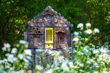 Manmade insect hotel in a green forest and flowers