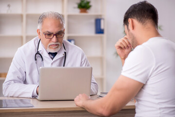 Obraz premium Young male patient visiting old male doctor