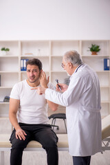 Fototapeta premium Young male doctor visiting old doctor otolaryngologist