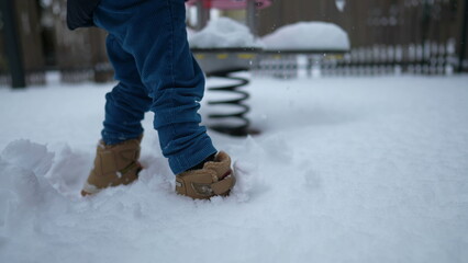 Child wearing boots walking in snow outside during winter season