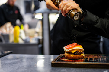 chef hand cooking cheeseburger on restaurant kitchen