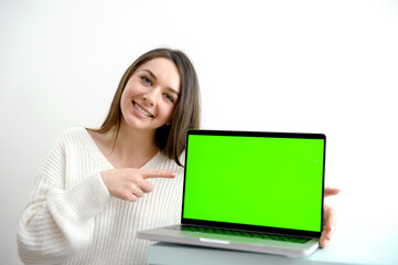 Naklejka premium girl pointing her finger at the screen of a laptop computer monitor Rear view woman freelancer using laptop computer with a green screen on monitor. Concept remote work, freelance, working on laptop