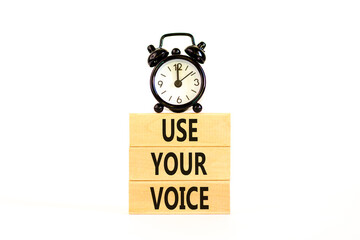 Use your voice symbol. Concept words Use your voice on wooden blocks on a beautiful white table white background. Black alarm clock. Business and use your voice concept. Copy space.