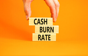 Cash burn rate symbol. Concept words Cash burn rate on wooden blocks on a beautiful orange table orange background. Businessman hand. Business cash burn rate concept. Copy space.