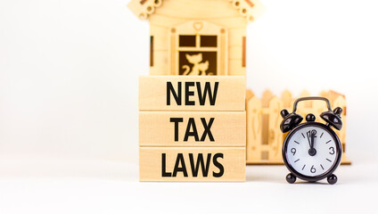 New tax laws symbol. Concept words New tax laws on wooden blocks on a beautiful white table white background. Black alarm clock, house model. Business new tax laws concept. Copy space.