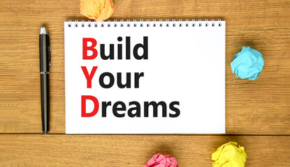 BYD build your dreams symbol. Concept words BYD build your dreams on white note on a beautiful wooden table wooden background. Pen. Business and BYD build your dreams concept. Copy space.