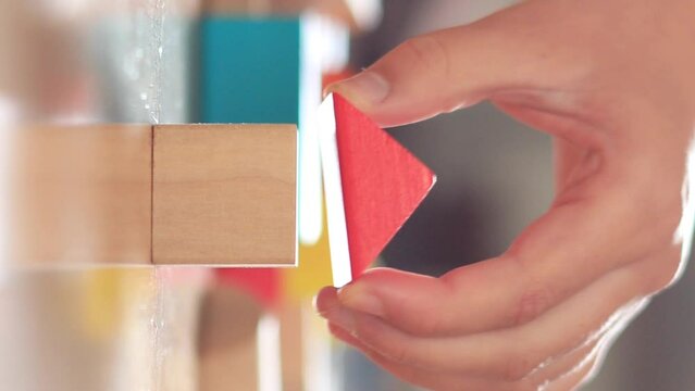 Close-up of girl's hand building house with wooden blocks Vertical video