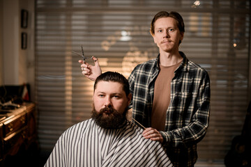 view of bearded man client and male barber with comb and scissors