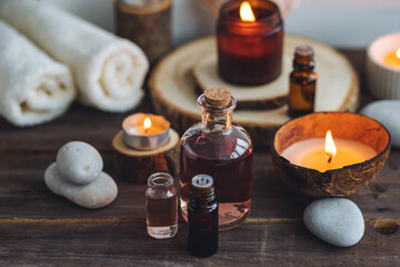 Concept of natural essential organic oils, Bali spa, beauty treatment, relax time. Atmosphere of relaxation, pleasure. Candles, towels, dark wooden background. Alternative oriental medicine