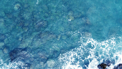 Fototapeta premium Aerial view of the ocean water surface and waves. Beautiful water background texture for tourism and advertising. Tropical coast