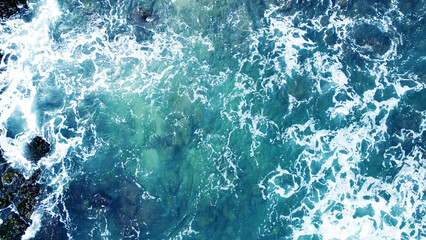 Obraz na płótnie Canvas Aerial view of the ocean water surface and waves. Beautiful water background texture for tourism and advertising. Tropical coast