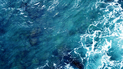 Aerial view of the ocean water surface and waves. Beautiful water background texture for tourism and advertising. Tropical coast - obrazy, fototapety, plakaty